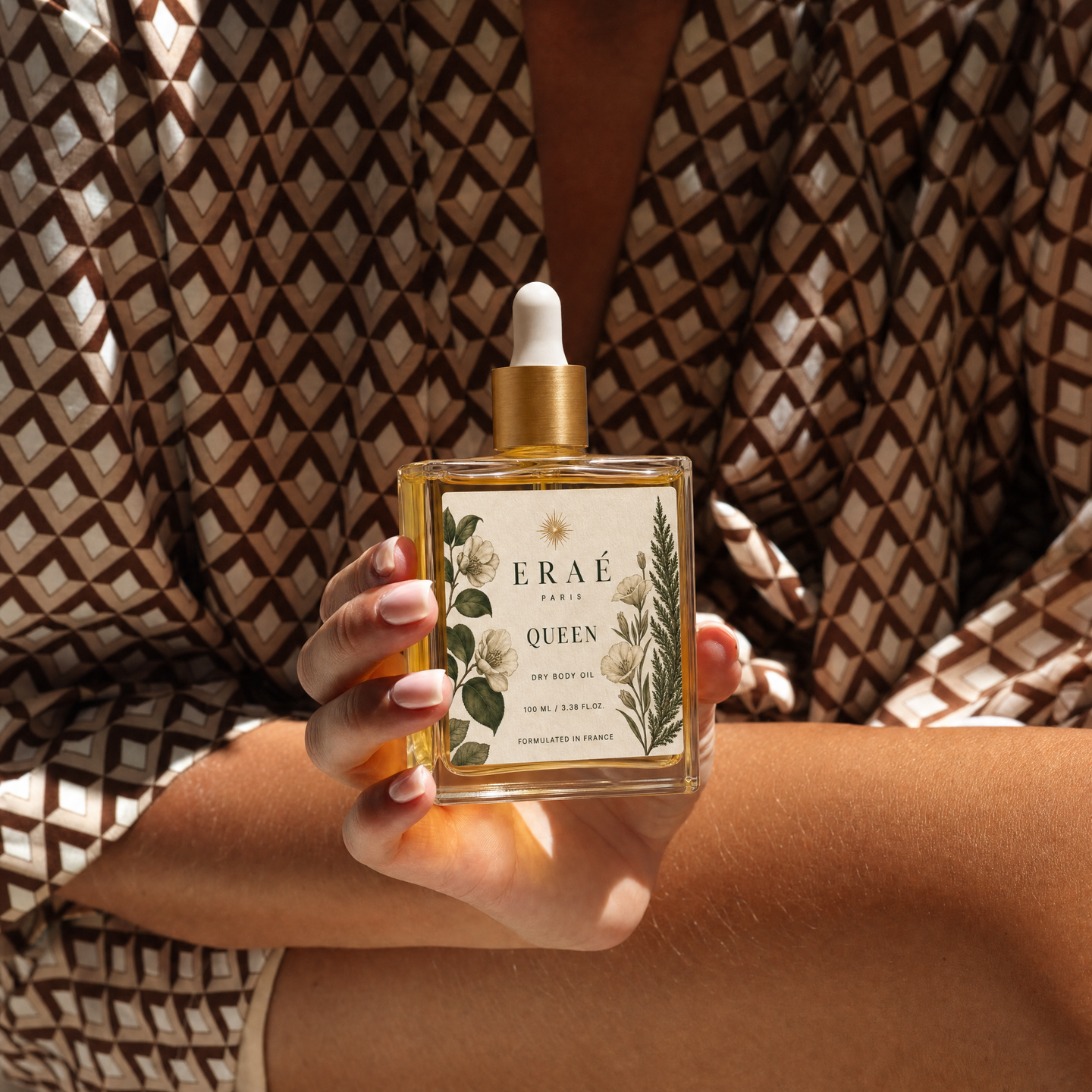 Eraé Queen Oil 120ml glass bottle on a bedroom dresser in afternoon light